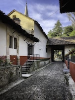 Una calle empedrada que lleva a un edificio con fachada blanca y base roja.