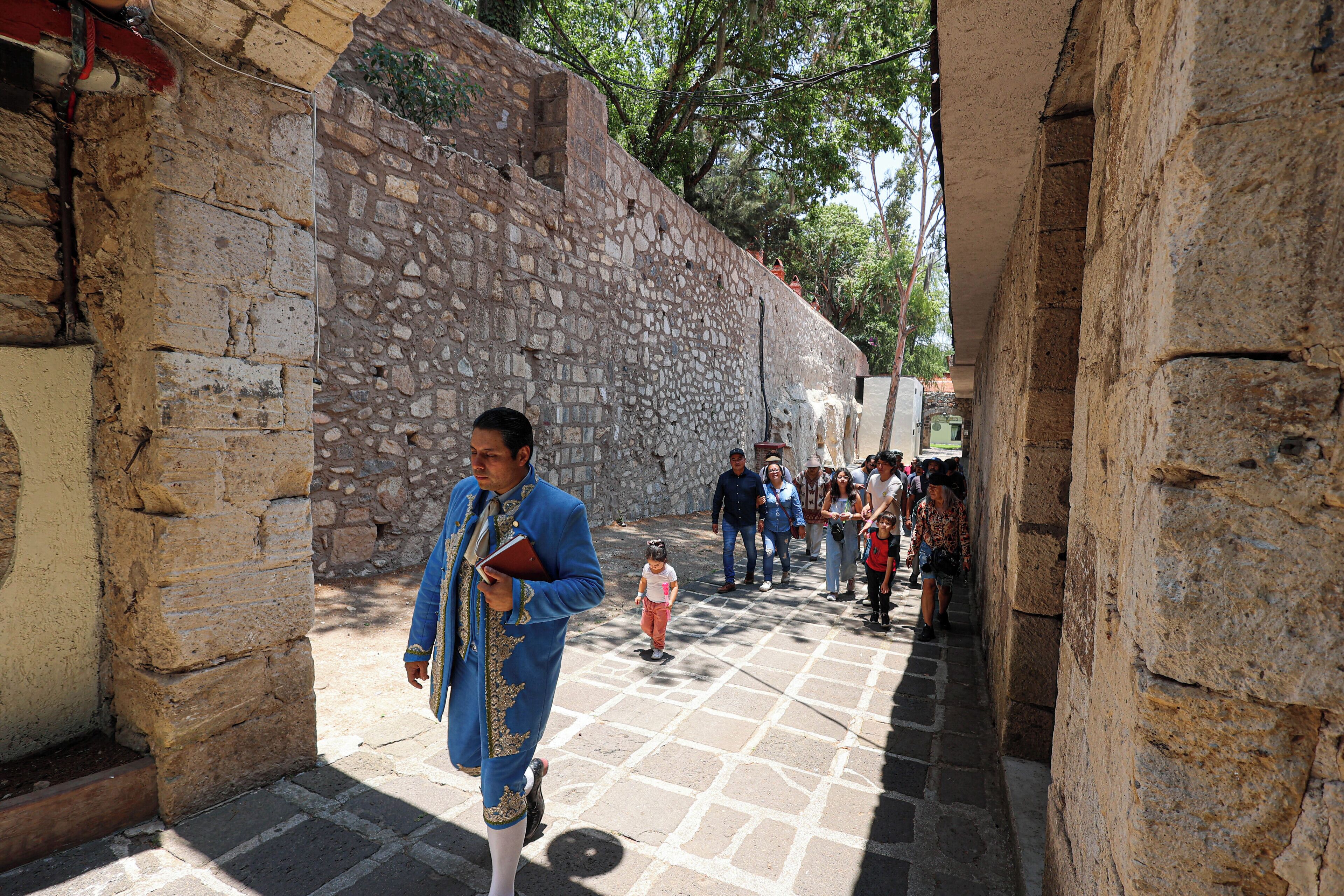 A narrow stone pathway with people walking, a man in a blue outfit, and a child.