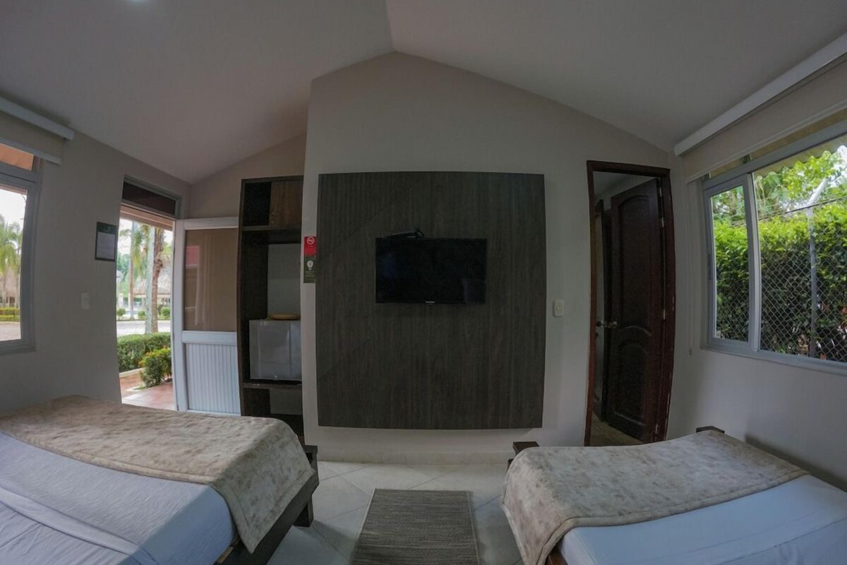 Een slaapkamer met twee bedden, een televisie en een groot raam.