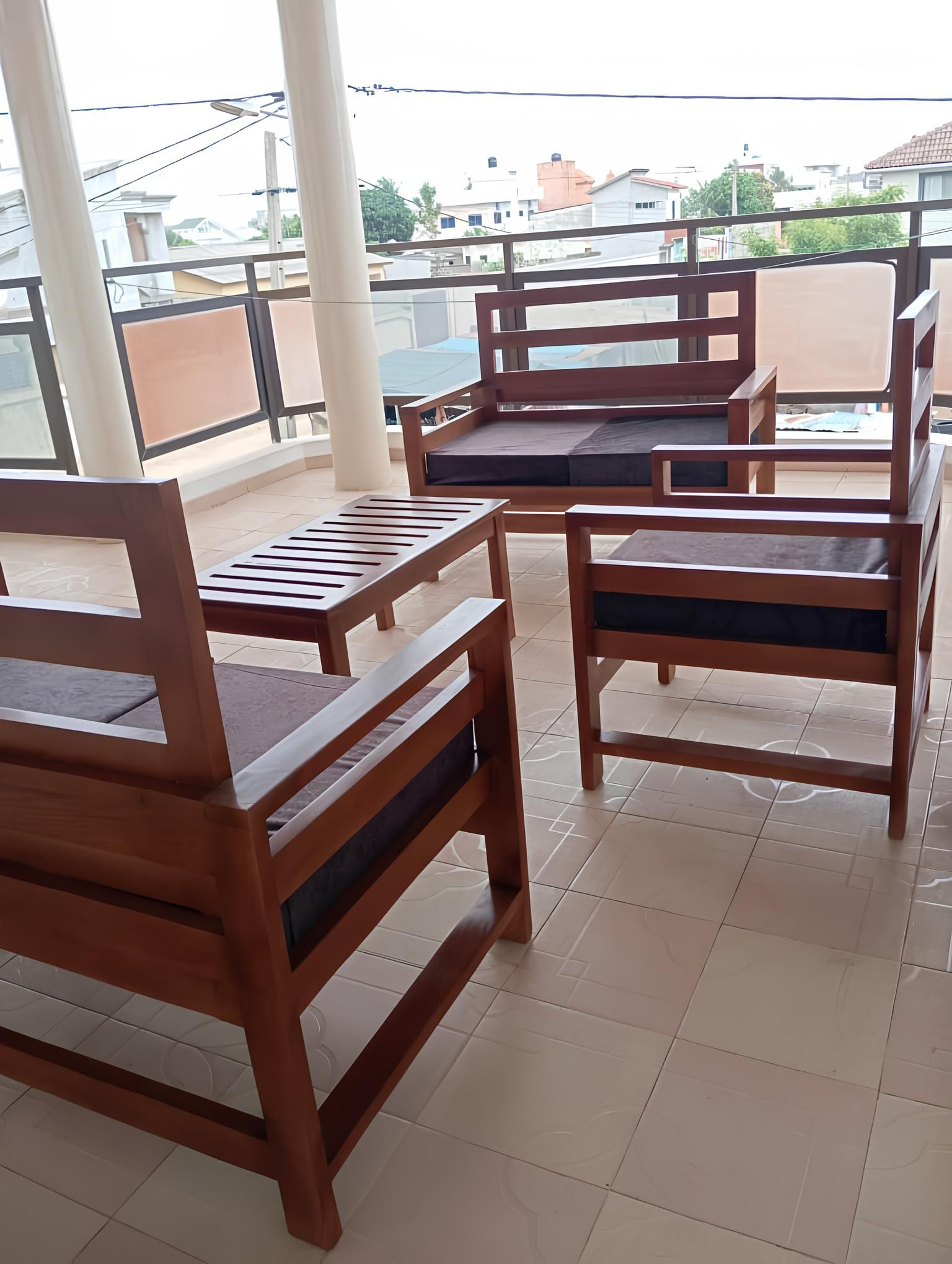 Een balkon met houten meubels, waaronder stoelen en een tafel.