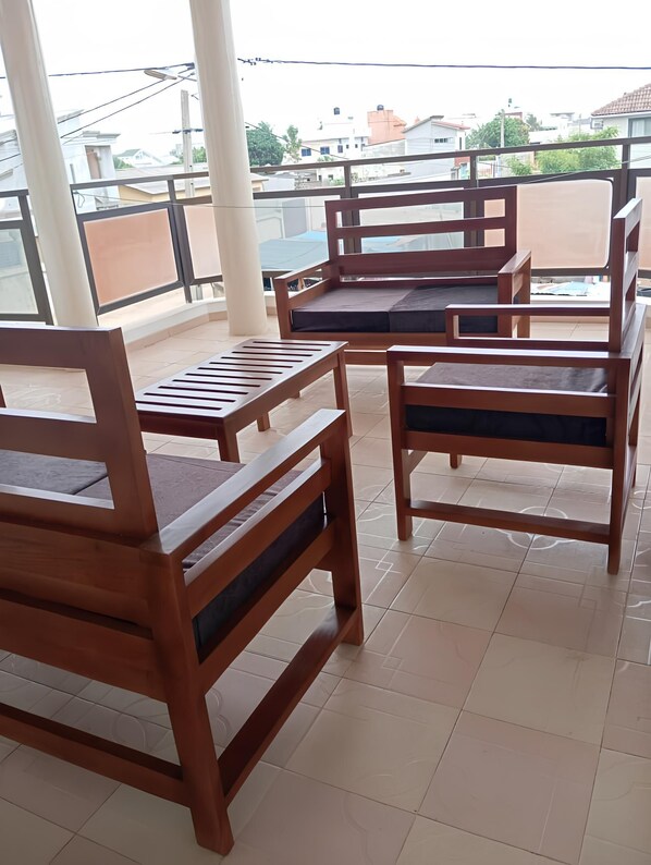 A balcony with wooden furniture, including chairs and a table. - 5 min walk from fidjrossè beach, ideal apartment for families (Cotonou)