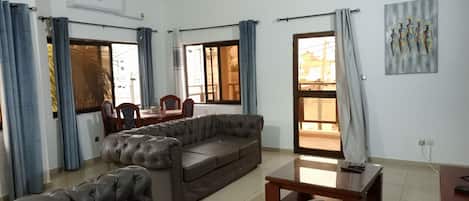 A living room with a sofa, a coffee table, and a dining area with chairs and a table.