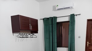 Een slaapkamer met een bed, een kledingkast, een tafeltje en een raam met gordijnen.