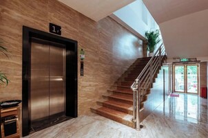 Un ascensor, una escalera y una zona de recepción con un cartel que indica el piso.