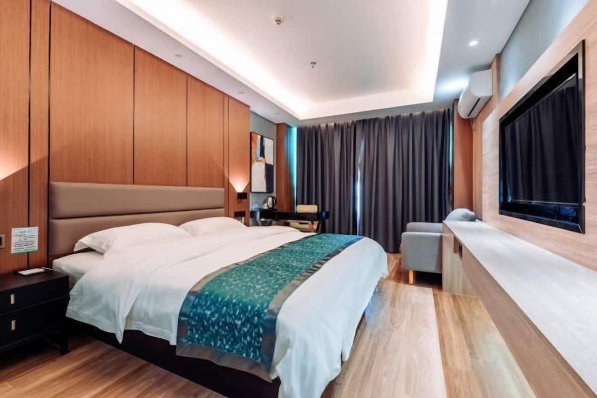 A modern hotel room with a large bed, a bedside table, a desk, and a window with curtains.