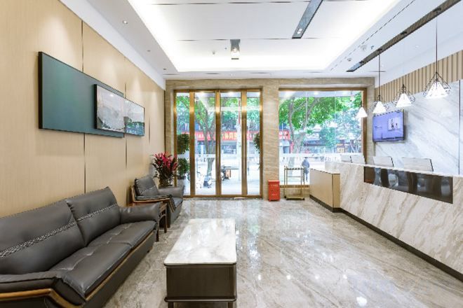 Un vestíbulo de hotel con una mesa de recepción, un sofá, una mesita de café y un amplio ventanal con vistas al exterior.