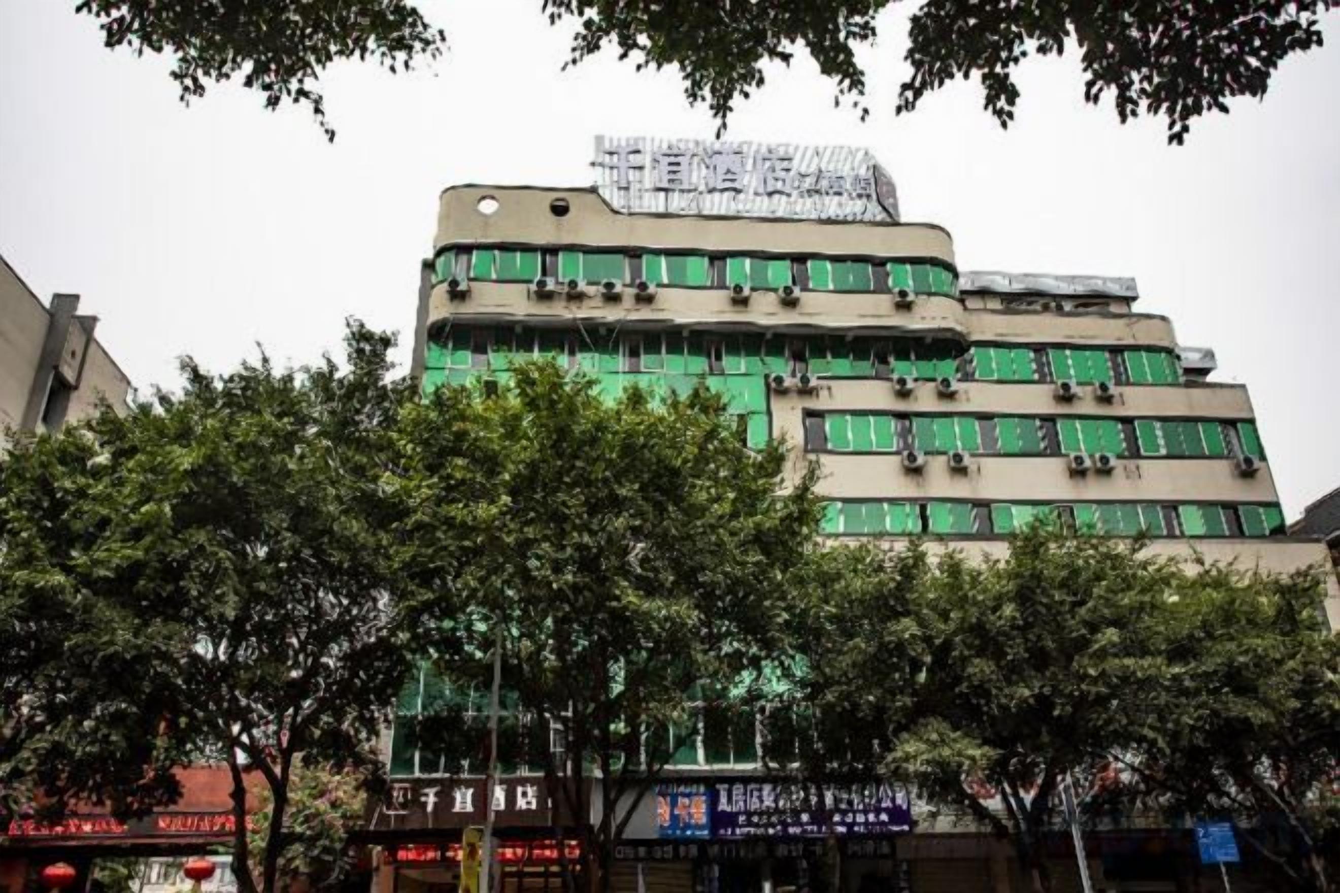 A multi-story building with a flat facade, large windows, and a sign on the top.
