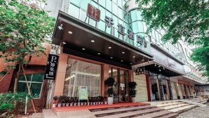 A hotel entrance with a modern facade, large glass windows, and a red carpet leading to the entrance. - Qianyi Hotel (Yulin Jiangnan Branch) (Yulin)