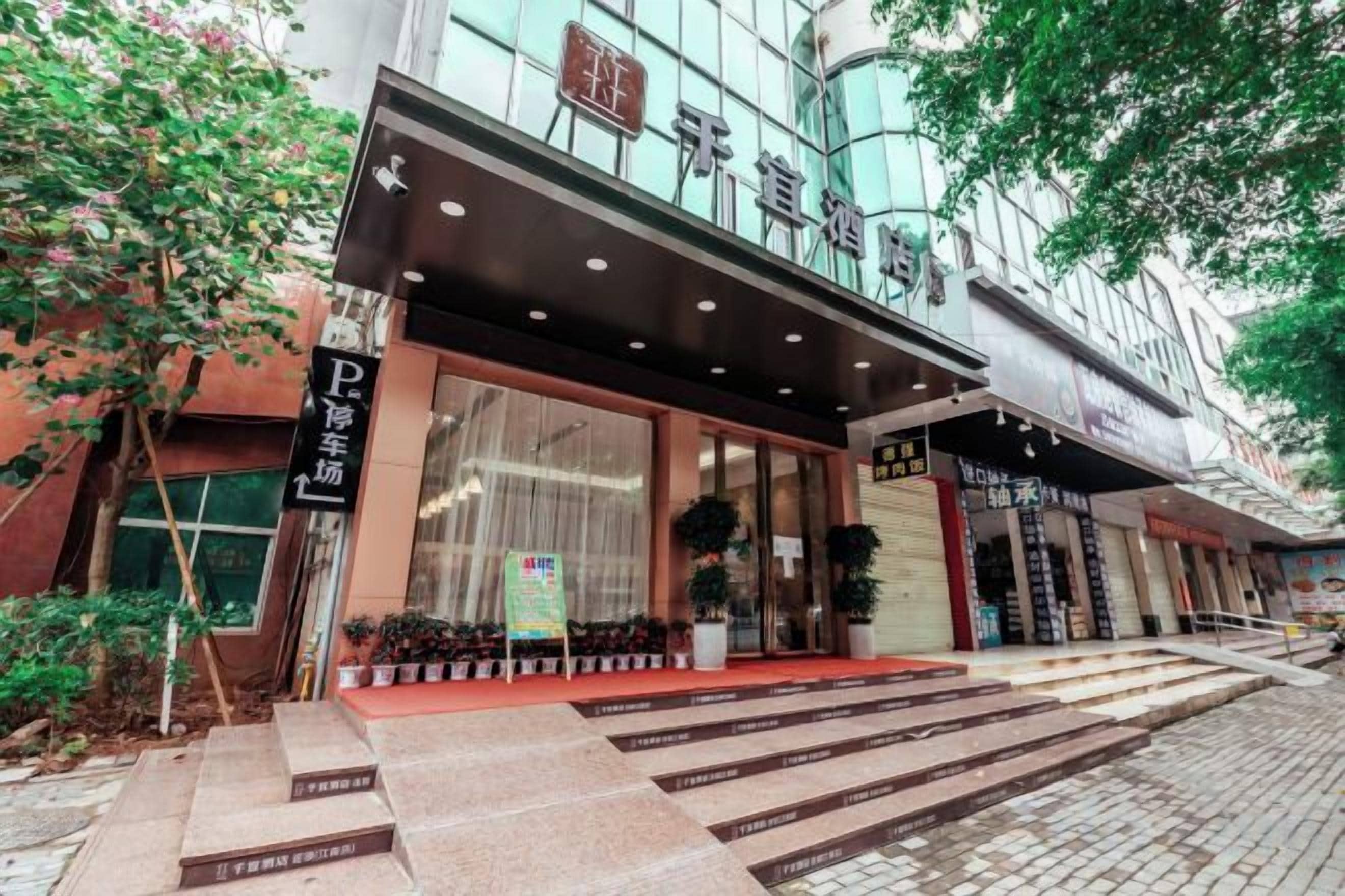 A hotel entrance with a modern facade, a visible entrance, and a staircase leading to the entrance.