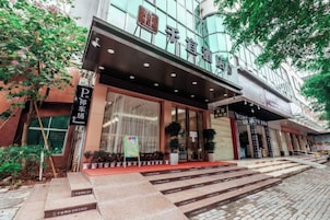 Una entrada de hotel con fachada moderna, visible y una escalera que conduce a ella.