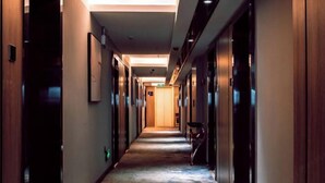 A hotel hallway with a carpeted floor, wooden doors, and a ceiling light. - Qianyi Hotel (Yulin Jiangnan Branch) (Yulin)