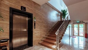 A modern lobby with a marble floor, a staircase, and an elevator. - Qianyi Hotel (Yulin Jiangnan Branch) (Yulin)