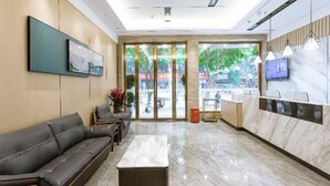 A modern lobby with a reception desk, seating area, and large windows offering a view of the outdoors. - Qianyi Hotel (Yulin Jiangnan Branch) (Yulin)