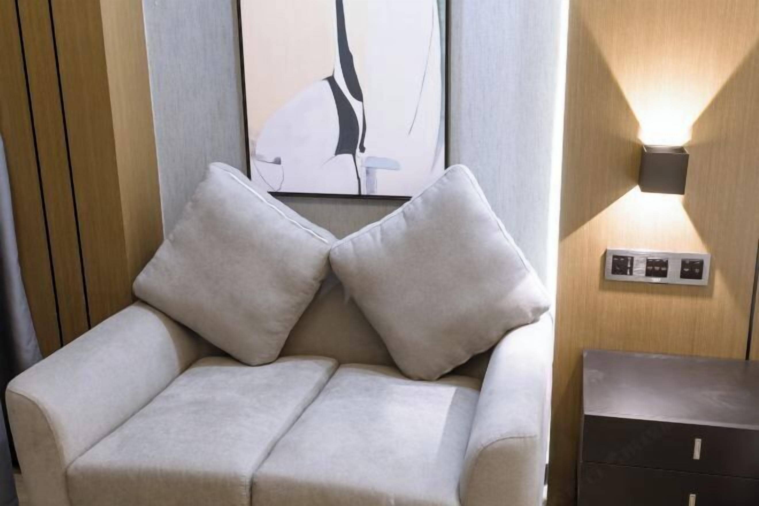 A modern room with a sofa, a wall-mounted light, and a framed artwork.