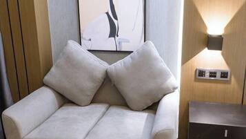 A modern room with a sofa, a wall-mounted light, and a framed artwork.