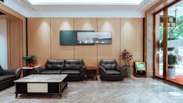 A modern hotel lobby with leather seating, a marble floor, and a large window.