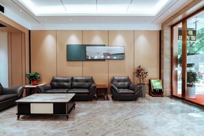 Eine moderne Hotellobby mit Ledersitzgelegenheiten, einem Marmorboden und einem großen Fenster.
