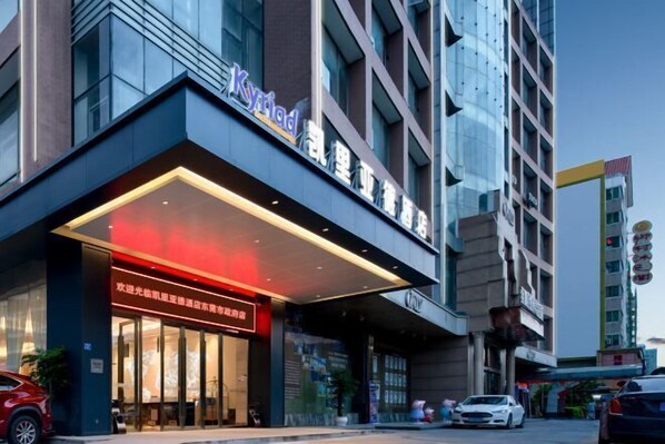A hotel with a modern facade, featuring a prominent sign and a well-lit entrance.