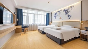 Ett hotellrum med två sängar, ett skrivbord, en stol, en världskarta på väggen och ett fönster med gardiner.