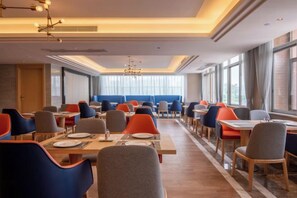 A hotel dining area with multiple tables and chairs, large windows, and a modern chandelier. - Kyriad Marvclous Hotel Dongguan Nancheng International Trade Center (Dongguan)