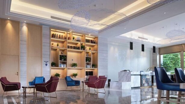 En modern entréhall med ett välpolerat golv, en sittgrupp och en väl upplyst receptionsdisk.