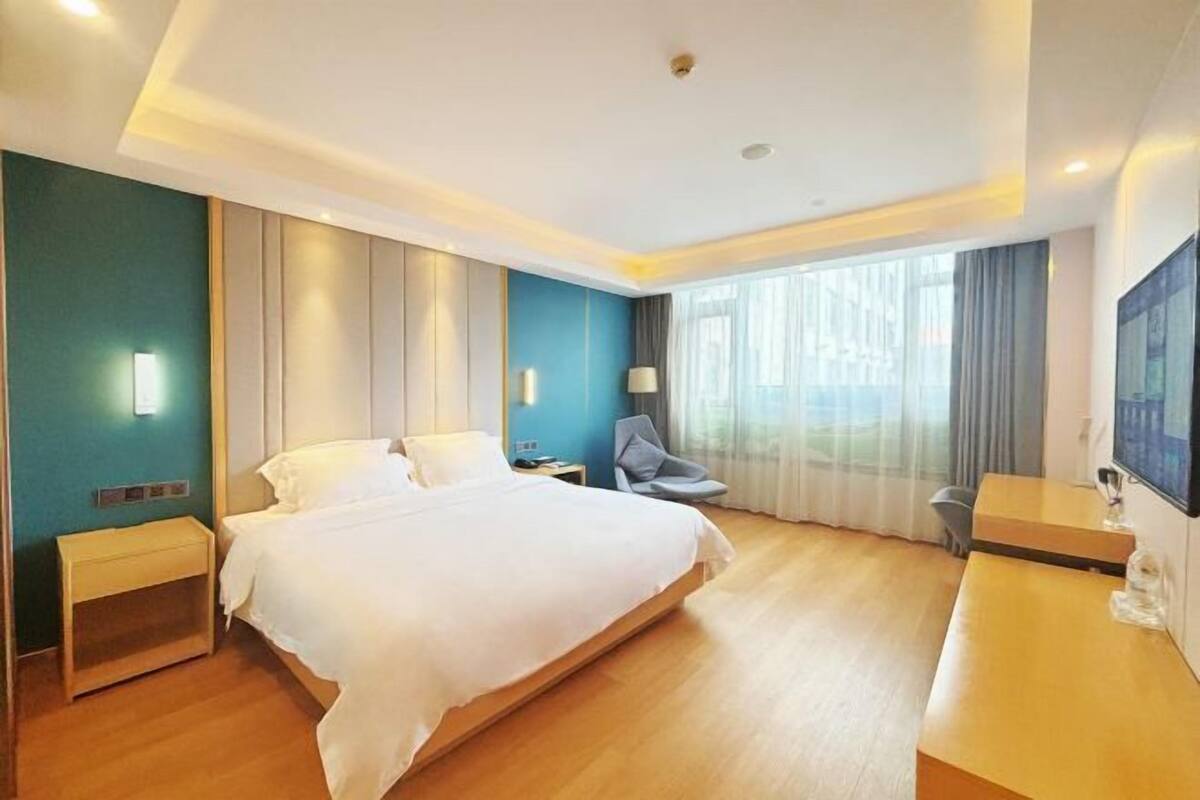 A modern hotel room with a large bed, bedside tables, a desk, and a chair.