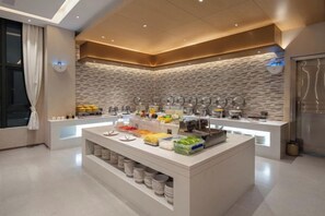 A buffet setup with various food items and beverages, a modern kitchen area, and a stone-patterned wall. - Lavande Hotel (Fangchenggang Dongxing Port Store) (Dongxing)