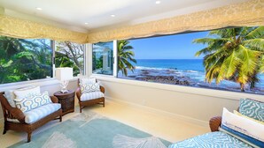 A room with wicker furniture, large windows, and a view of the ocean. - Luxury Oceanfront Private Estate, large family gatherings (Kailua-Kona)