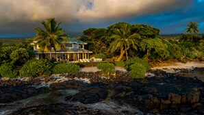 Une propriété située en bord de mer, comprenant une maison, des palmiers et une côte rocheuse.