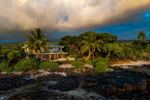 A beachfront property with a house, palm trees, and a rocky shoreline. - Luxury Oceanfront Private Estate, large family gatherings (Kailua-Kona)