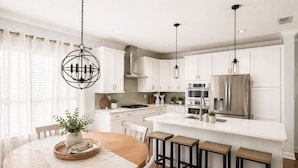 A modern kitchen with white cabinetry, a central island, and pendant lighting.