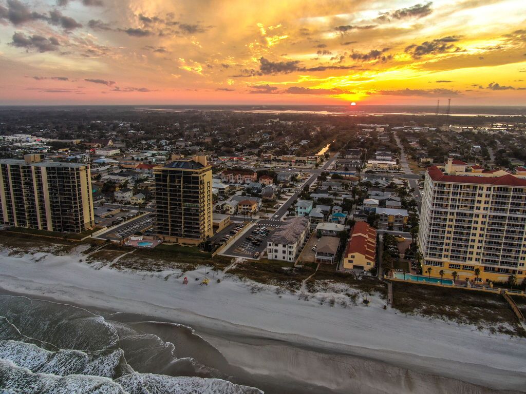 Un paysage urbain côtier avec de hauts immeubles, une plage et un coucher de soleil.