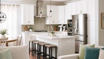 A modern kitchen with white cabinets, stainless steel appliances, and a central island with stools.