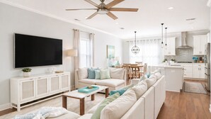 A modern living room with a sofa, TV, and dining area.