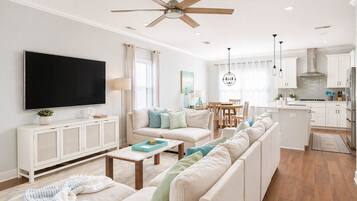 A modern living room with a sofa, TV, and dining area.