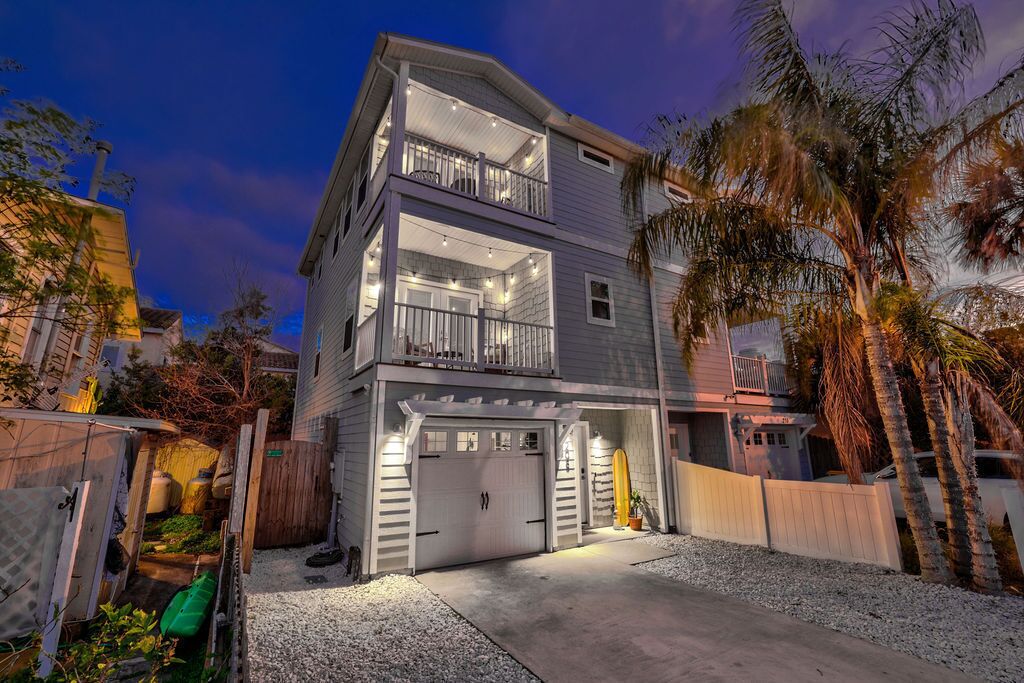 A multi-story residential building with a garage, balconies, and a driveway.