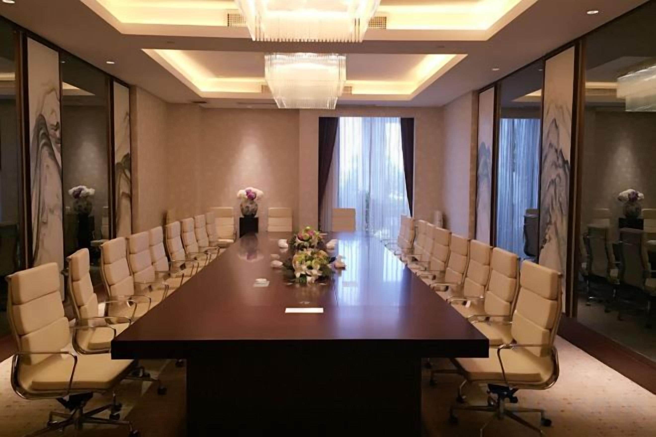 A conference room with a long table, chairs, and a chandelier.