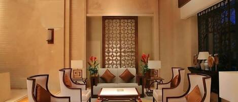 Un hall de hotel con una zona de estar central, una pared decorativa y vistas al exterior.