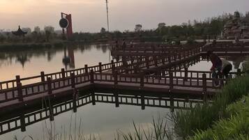 Ruhige Wasserfläche mit einer Holzbrücke und einer pagodähnlichen Struktur im Hintergrund.
