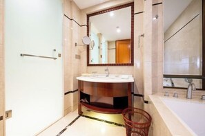 Un baño moderno con un tocador redondo, un espejo grande y una bañera independiente.