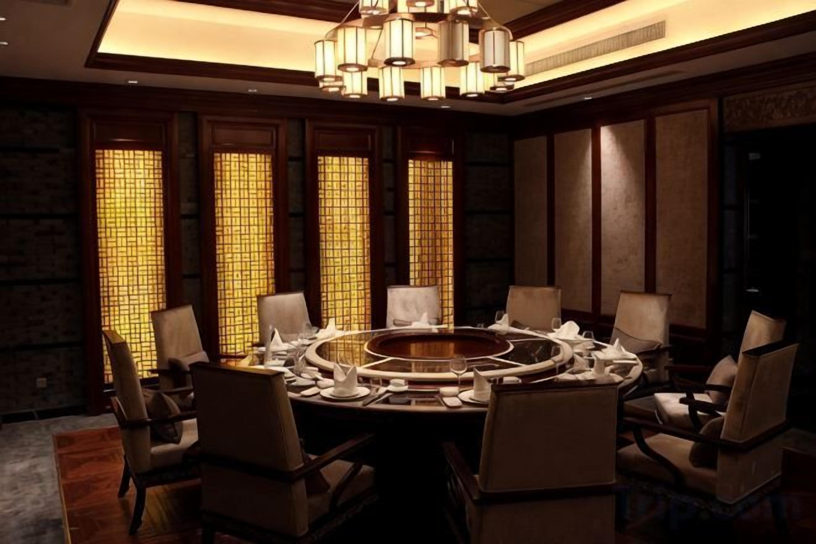 Sala de conferência com mesa redonda, cadeiras e lustre.