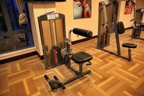 A gym with exercise equipment, a bench, and a window with a view. - Heanhu International Hotel (Lianyungang)
