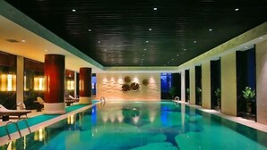 Una piscina interior con sillas de descanso y una pared decorada con motivos circulares.