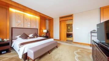 A hotel room with a large bed, a television, and a wooden panel wall.