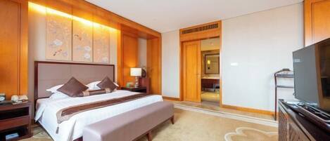A hotel room with a large bed, a television, and a wooden panel wall.