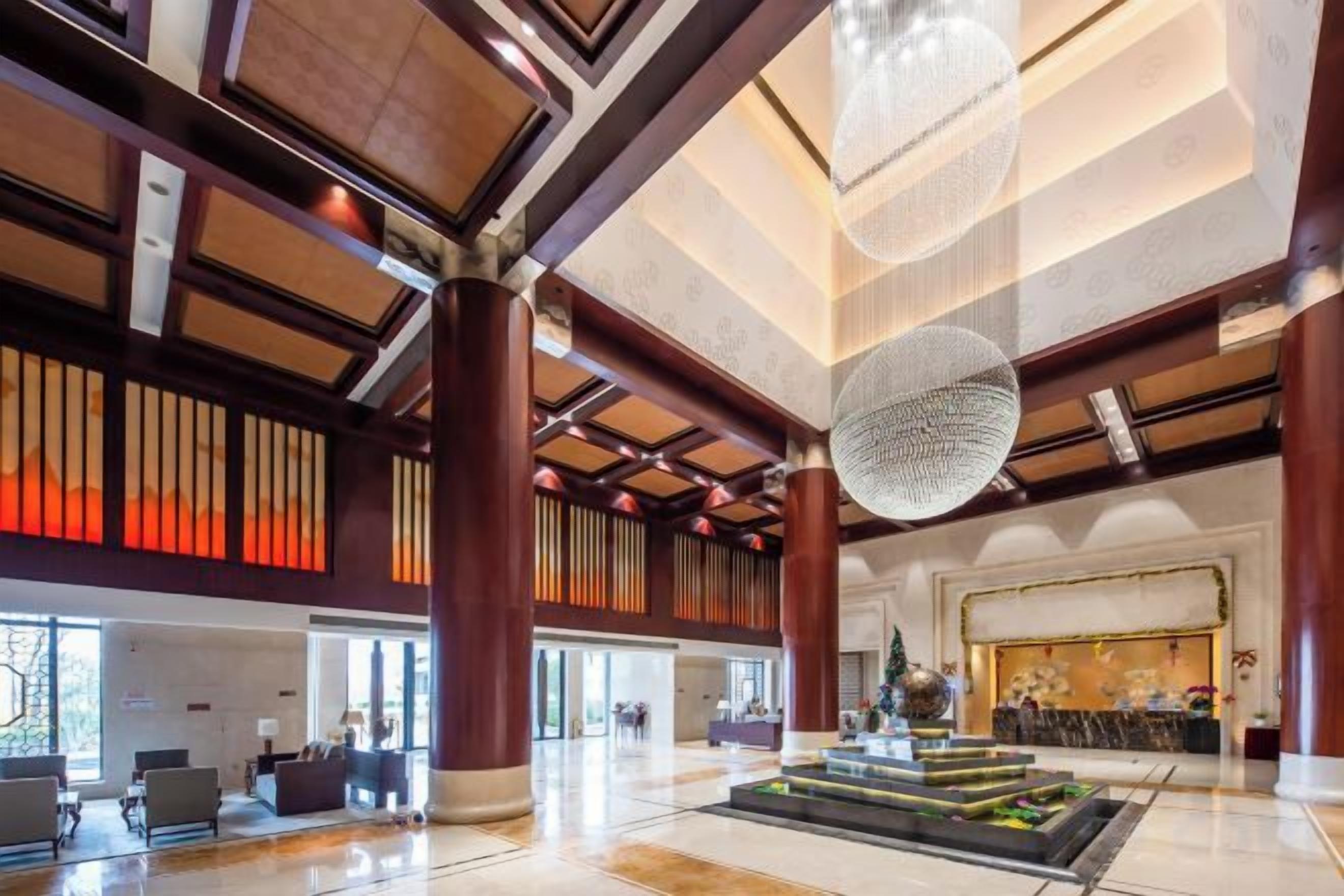 A spacious lobby with high ceilings, large columns, and a central fountain.