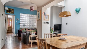Uma sala de estar acolhedora com uma mesa de jantar de madeira, um sofá e uma televisão.
