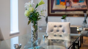 Et glastop med en vase fyldt med hvide blomster og grønne blade.