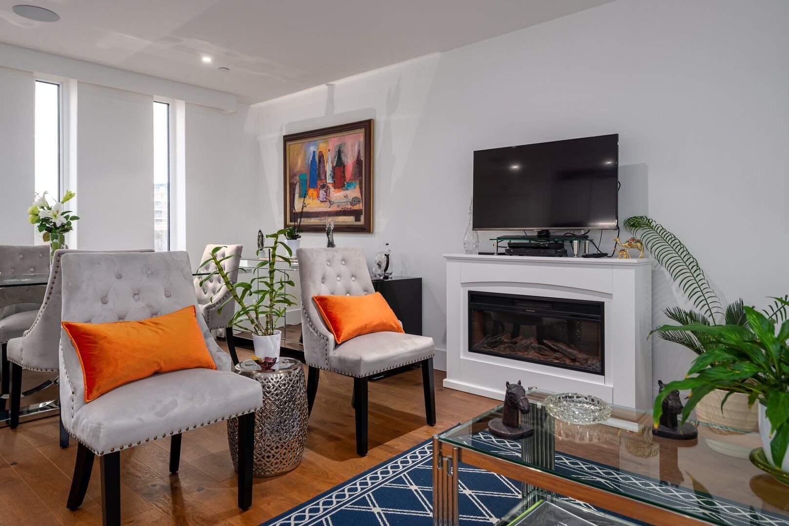 A modern living room with a fireplace, comfortable seating, and a flat-screen TV.
