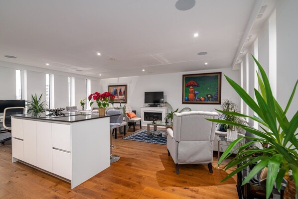Un salon moderne avec un îlot de cuisine, une cheminée et une grande fenêtre.